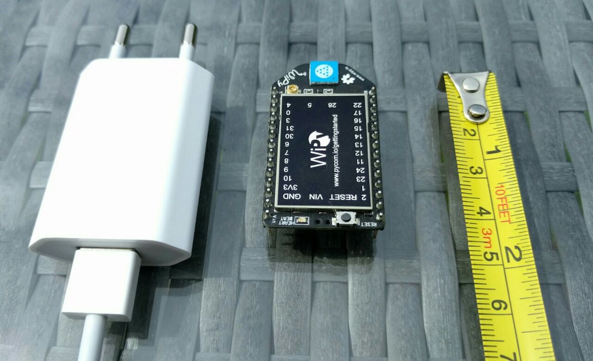 Picture of WiPy chip with USB power adapter and measuring tape for reference.